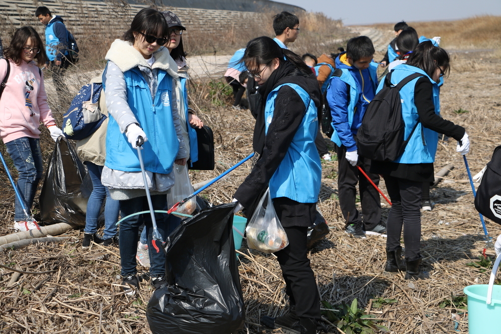 我校志愿者认真清理海岸上的垃圾