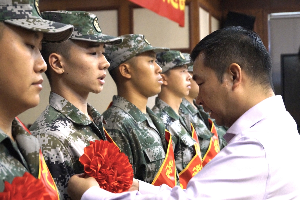 李志鹏为入伍学生佩戴大红花并发放慰问品